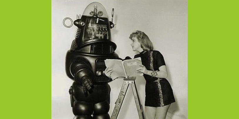 Woman and robot standing on an a-frame ladder looking at a book together