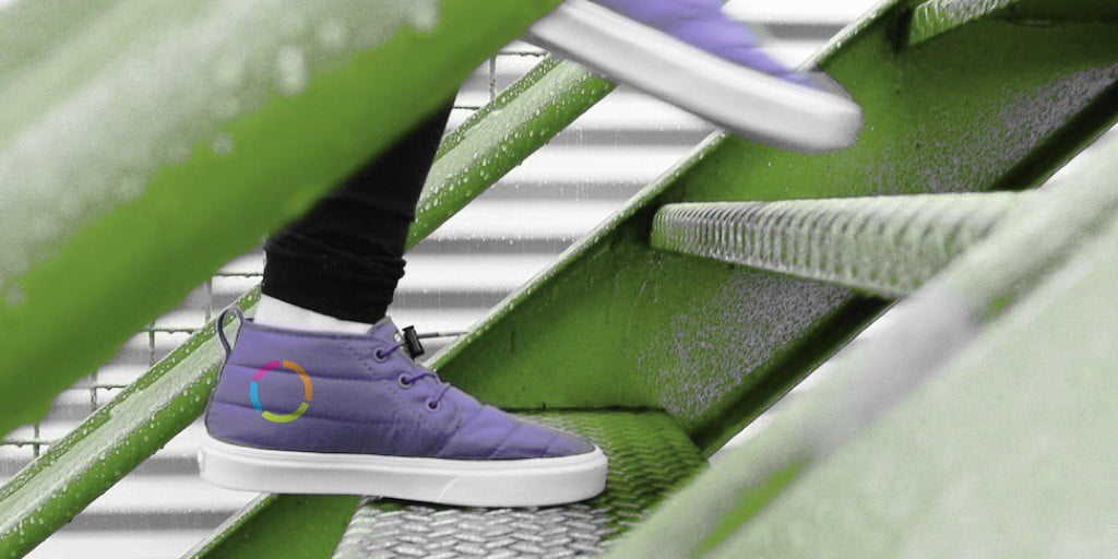 Person climbing metal stairs in a pair of purple shoes with the textio logo on the side